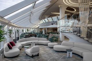 Ein stilvoller Sitzbereich im MSC Yacht Club mit eleganten Sofas und einer beeindruckenden Glaswand | MSC Cruises