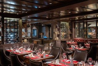 An elegant restaurant setting with tables, chairs and wine bottles ready for guests on MSC World Asia | MSC Cruises