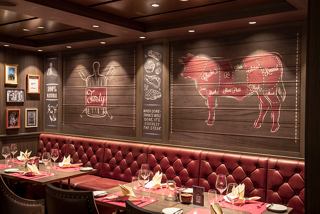 Elegant dining area featuring a warm atmosphere with red accents and stylish decor in the Butcher's Cut restaurant | MSC Cruises
