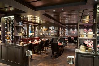An inviting steakhouse interior with tables and chairs set for dining, showcasing a warm atmosphere | MSC Cruises