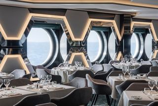 A stylish dining area with hexagonal windows offering views of the sea and sky | MSC Cruises