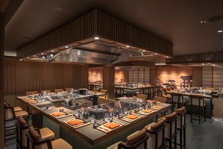 A warm and inviting interior of the Kaito Teppanyaki restaurant, featuring a central cooking area and elegant wooden decor | MSC Cruises