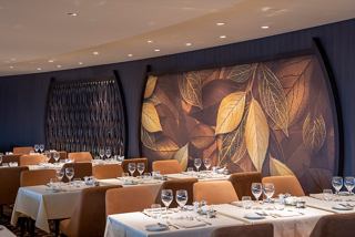 Elegant dining setup in La Foglia Restaurant with tables and chairs, featuring a warm atmosphere | MSC Cruises