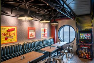 A stylish interior of a restaurant featuring seating, artwork, and a porthole, inviting guests to enjoy their meals | MSC Cruises