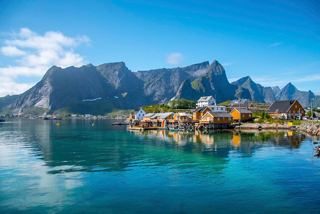 A scenic view of Leknes in Lofoten, Norway, showcasing mountains, sea, and charming houses by the water | MSC Cruises