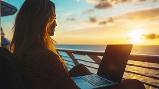 A woman works on a laptop on deck, enjoying the sunset over the sea | MSC Cruises