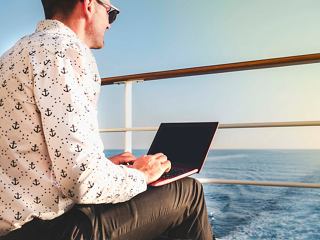A man works on his laptop at sea, enjoying the serene view from the ship's deck | MSC Cruises