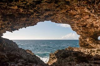 A natural arch frames a view of the serene sea beyond, highlighting the beauty of Barbados' coastline | MSC Cruises