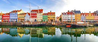 Edificios coloridos bordean el puerto de Nyhavn, reflejándose bellamente en las aguas tranquilas, invitando a la exploración y la aventura | MSC Cruceros