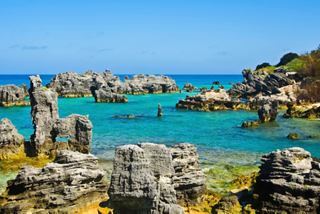 Crystal-clear turquoise waters gently lap against rugged rocks in Bermuda's stunning coastline | MSC Cruises