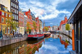 Encantadora vista del canal en Ámsterdam con edificios coloridos a lo largo del agua y barcos deslizándose | MSC Cruceros