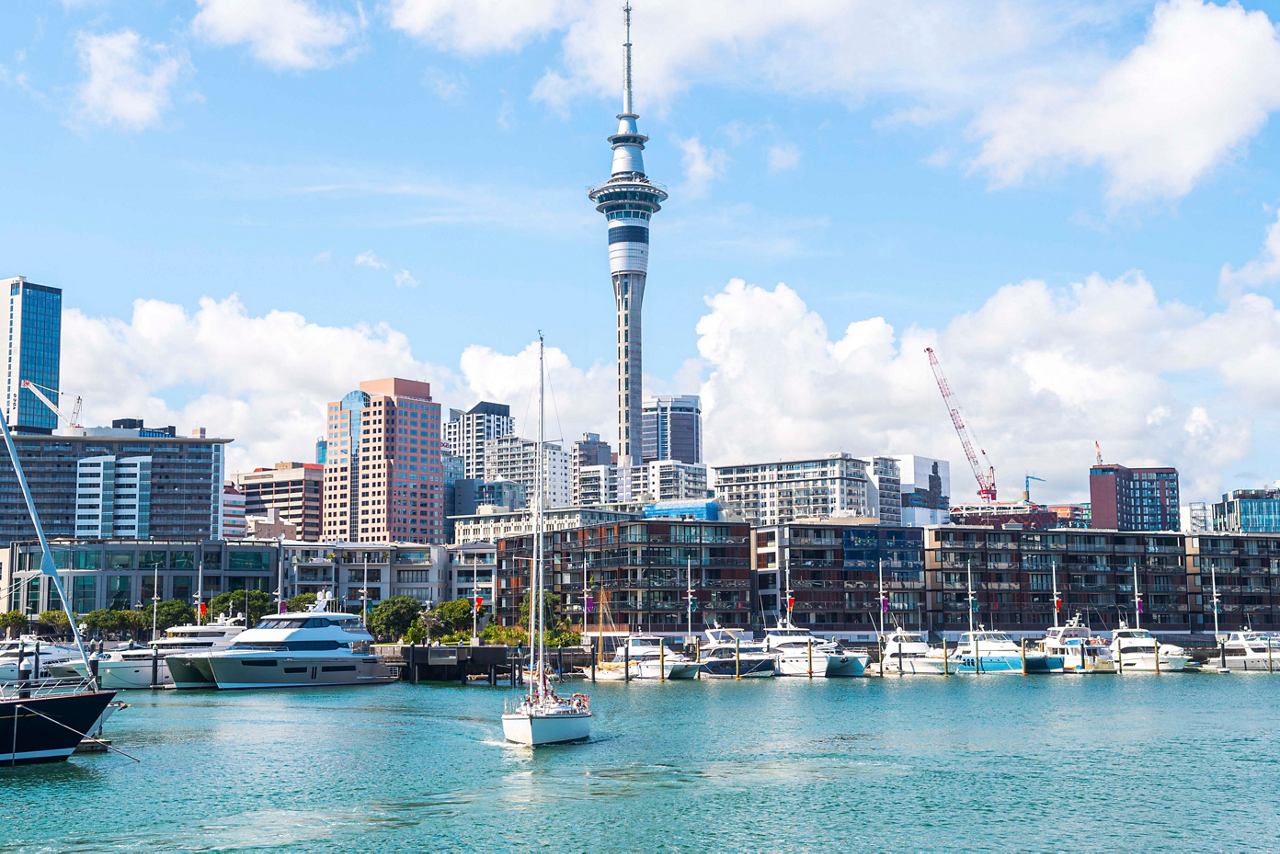 Auckland's vibrant skyline features the Sky Tower, with boats at the pier and a bright blue sky above | MSC Cruises