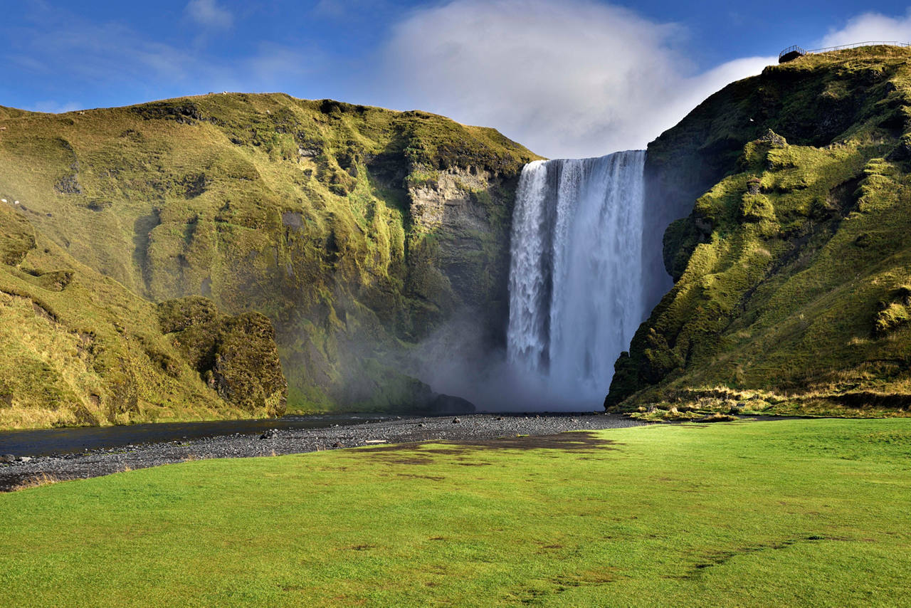 Majestic Skogafoss waterfall cascading down lush green cliffs in Iceland's serene landscape | MSC Cruises