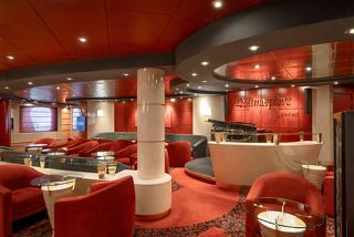 A stylish lounge area with comfortable seating and a piano, inviting guests to relax and enjoy the atmosphere | MSC Cruises