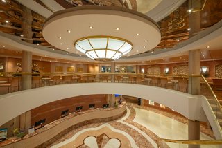 Elegant multi-level lounge area with a bar counter and seating, featuring a piano and warm lighting | MSC Cruises