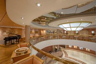 A spacious lounge area featuring comfortable seating, a piano, and a welcoming bar counter | MSC Cruises