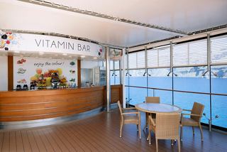 A welcoming lounge area with a reception desk and seating, overlooking the sea through large glass windows | MSC Cruises