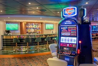 A vibrant casino area featuring a slot machine and a bar counter for entertainment on MSC Lirica | MSC Cruises