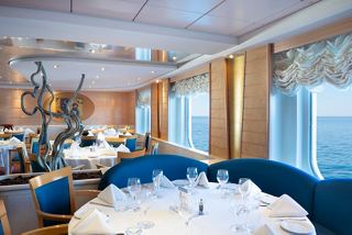 A luxurious dining setting with elegant furnishings and a view of the sea through a porthole | MSC Cruises