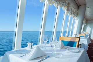 A serene restaurant setting aboard MSC Lirica, featuring a table and chairs with a stunning sea view | MSC Cruises