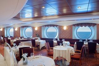 Elegant dining area with tables set for guests, portholes offering sea views, creating a welcoming atmosphere | MSC Cruises