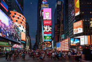 Ein lebendiger Times Square in der Dämmerung, gefüllt mit Menschen, erleuchtet von hellen Bildschirmen und hohen Wolkenkratzern | MSC Cruises