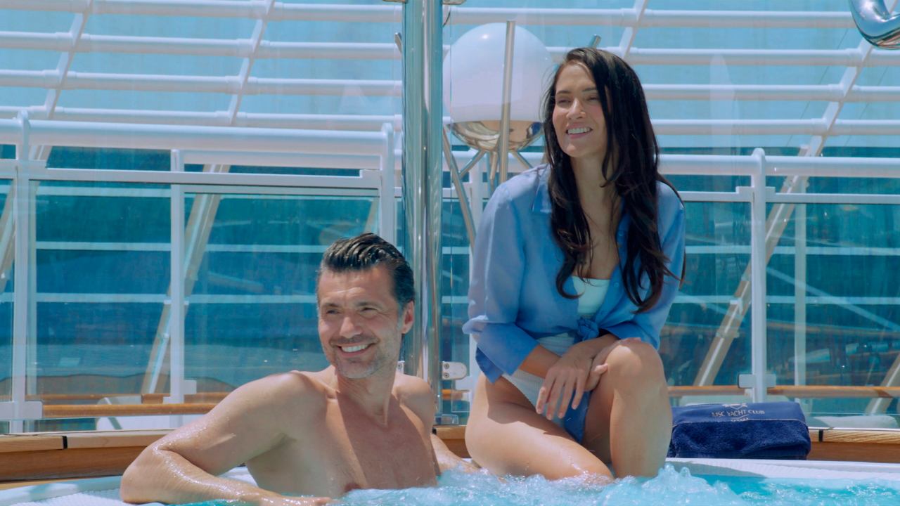 A man and woman relax together by the pool, enjoying life aboard MSC Yacht Club | MSC Cruises