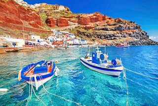 Des bateaux tanguent doucement dans des eaux claires près des superbes falaises de la côte de Santorin | MSC Croisières
