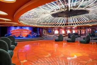 A vibrant lounge area with seating and a stage, perfect for entertainment and relaxation aboard MSC Fantasia | MSC Cruises