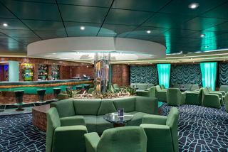 A stylish lounge area with green armchairs and sofas, perfect for relaxation and socialising aboard MSC Fantasia | MSC Cruises