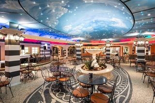 A vibrant sitting area in Piazza San Giorgio, featuring plants, a fountain, tables, and comfortable chairs for relaxation | MSC Cruises