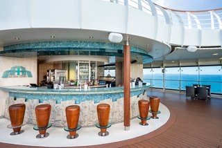 An inviting outdoor bar area on MSC Fantasia with a sleek counter and comfortable seating overlooking the sea | MSC Cruises