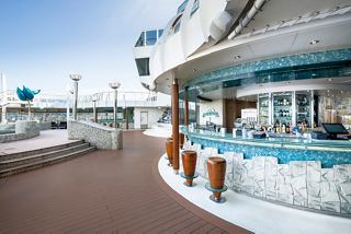 A relaxing outdoor bar area on the MSC Fantasia featuring seating and a bar counter for guests to enjoy | MSC Cruises