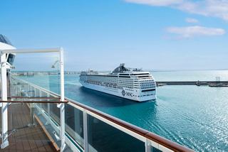 Vista desde el balcón que muestra el MSC Orchestra anclado en aguas serenas bajo un cielo azul claro | MSC Cruceros