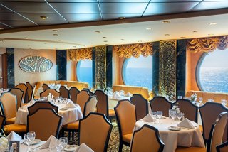 A warm dining area with elegant chairs and tables, featuring porthole windows overlooking the sea | MSC Cruises