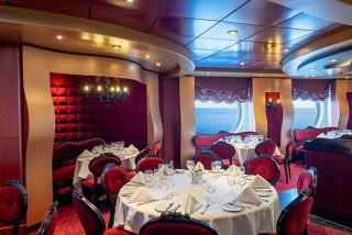 Elegant dining area with round table, red velvet chairs and a scenic view through the porthole | MSC Cruises