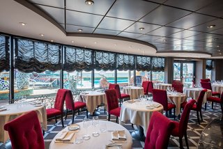 Elegant dining area with red chairs and tables, featuring large windows for stunning views | MSC Cruises