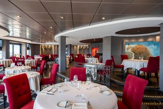 Elegant dining area featuring round tables and plush red chairs, inviting guests to enjoy a memorable meal | MSC Cruises