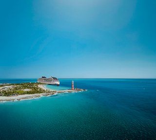 Vista aerea di Ocean Cay MSC Marine Reserve con un faro e MSC World America vicino al chiaro mare blu | MSC Crociere