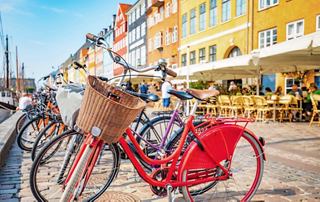 A cyclist enjoying a sunny day in Copenhagen near colourful buildings and parked bicycles | MSC Cruises