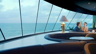 A couple enjoys a toast with drinks in the elegant Top Sail Lounge with a stunning sea view | MSC Cruises