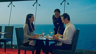 A couple enjoys a meal at a seaside restaurant while being served by a waitress | MSC Cruises