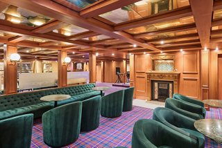 A welcoming lounge with comfortable seating areas, a stage for live music, and a warm atmosphere to relax | MSC Cruises