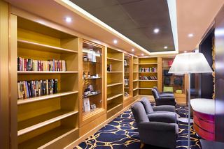 A cozy reading area features bookshelves, comfortable armchairs, and warm lighting, inviting relaxation and inspiration | MSC Cruises