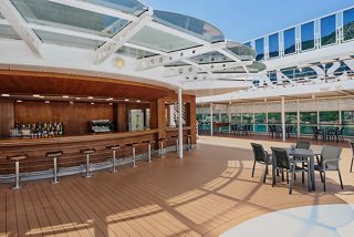 A welcoming outdoor seating area featuring the Il Lido Bar with chairs, tables, and a scenic view of the sea and sky | MSC Cruises