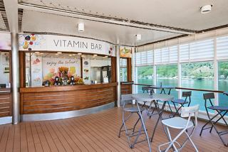 A welcoming sitting area at The Vitamin Bar with a wooden counter, tables, and views of the outdoors | MSC Cruises