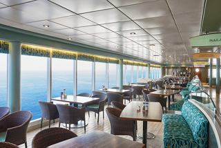A spacious dining area with large windows offering ocean views, showcasing tables and chairs for guests | MSC Cruises