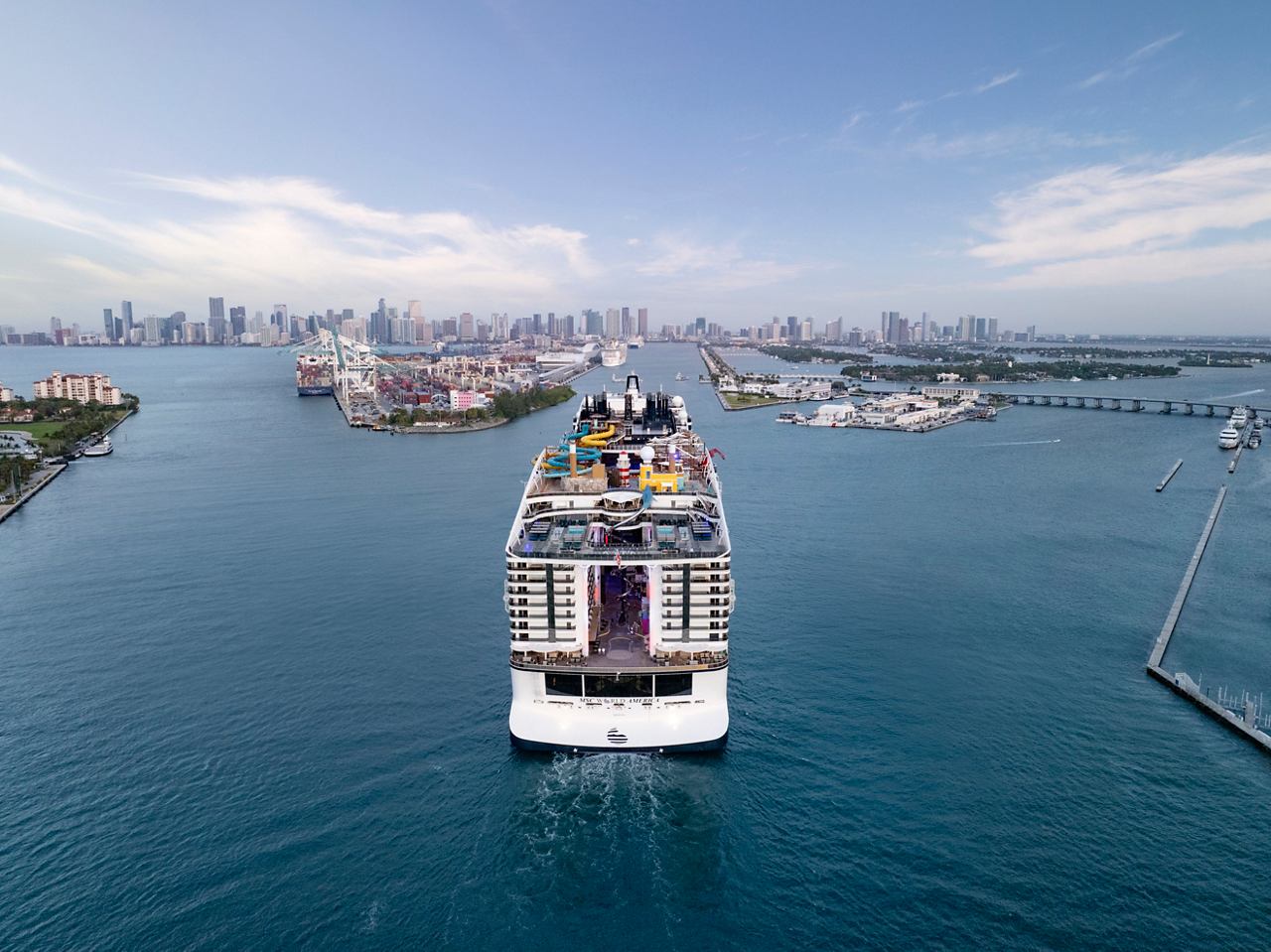 Vista aérea del MSC World America navegando en las vibrantes aguas cerca de Miami, mostrando el horizonte y los alrededores exuberantes | MSC Cruceros