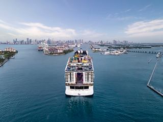 Vista aérea del MSC World America navegando en las vibrantes aguas cerca de Miami, mostrando el horizonte y los alrededores exuberantes | MSC Cruceros