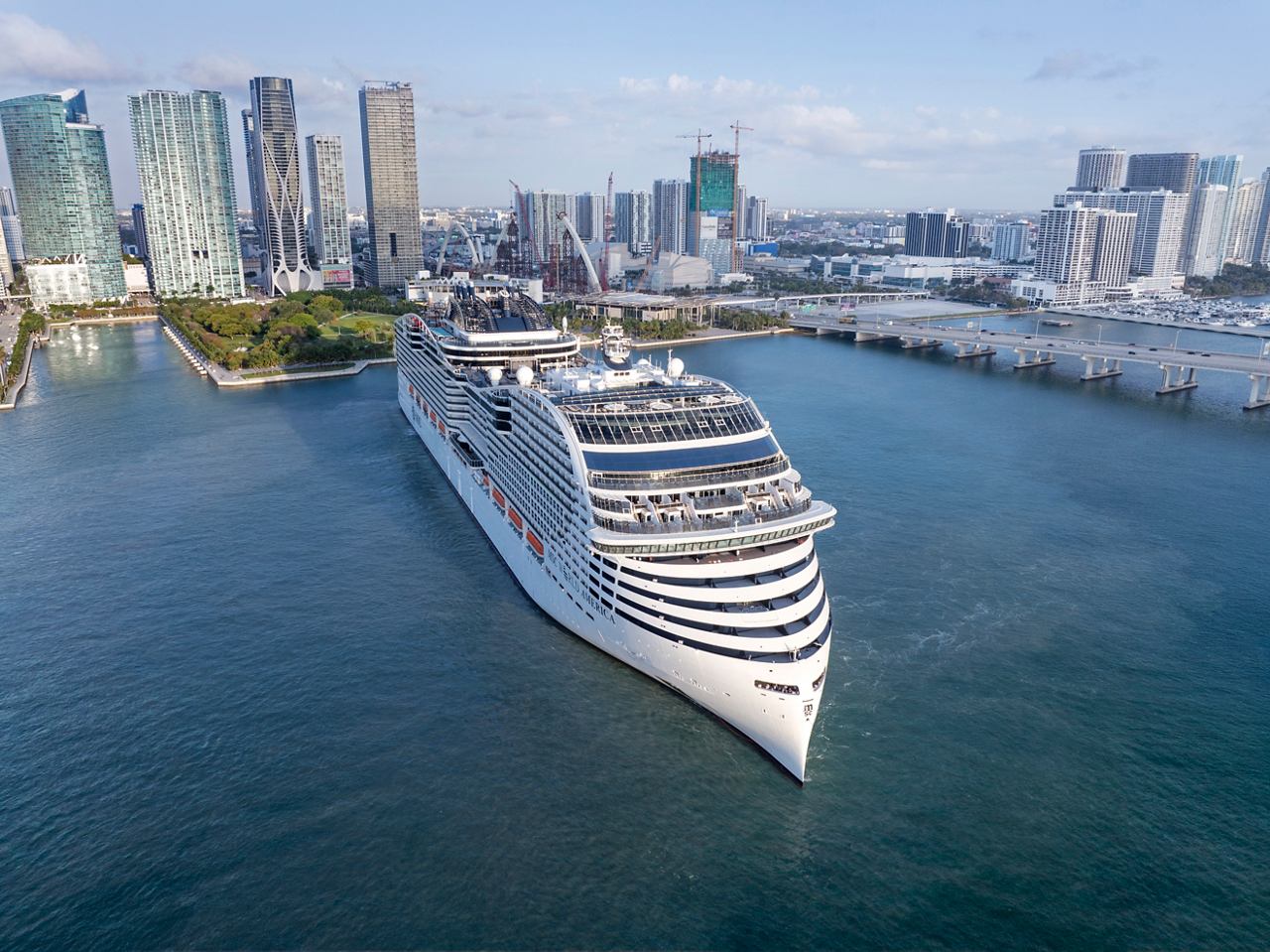 The MSC World America is docked in a vibrant Miami harbour, surrounded by stunning city skyline and blue waters | MSC Cruises